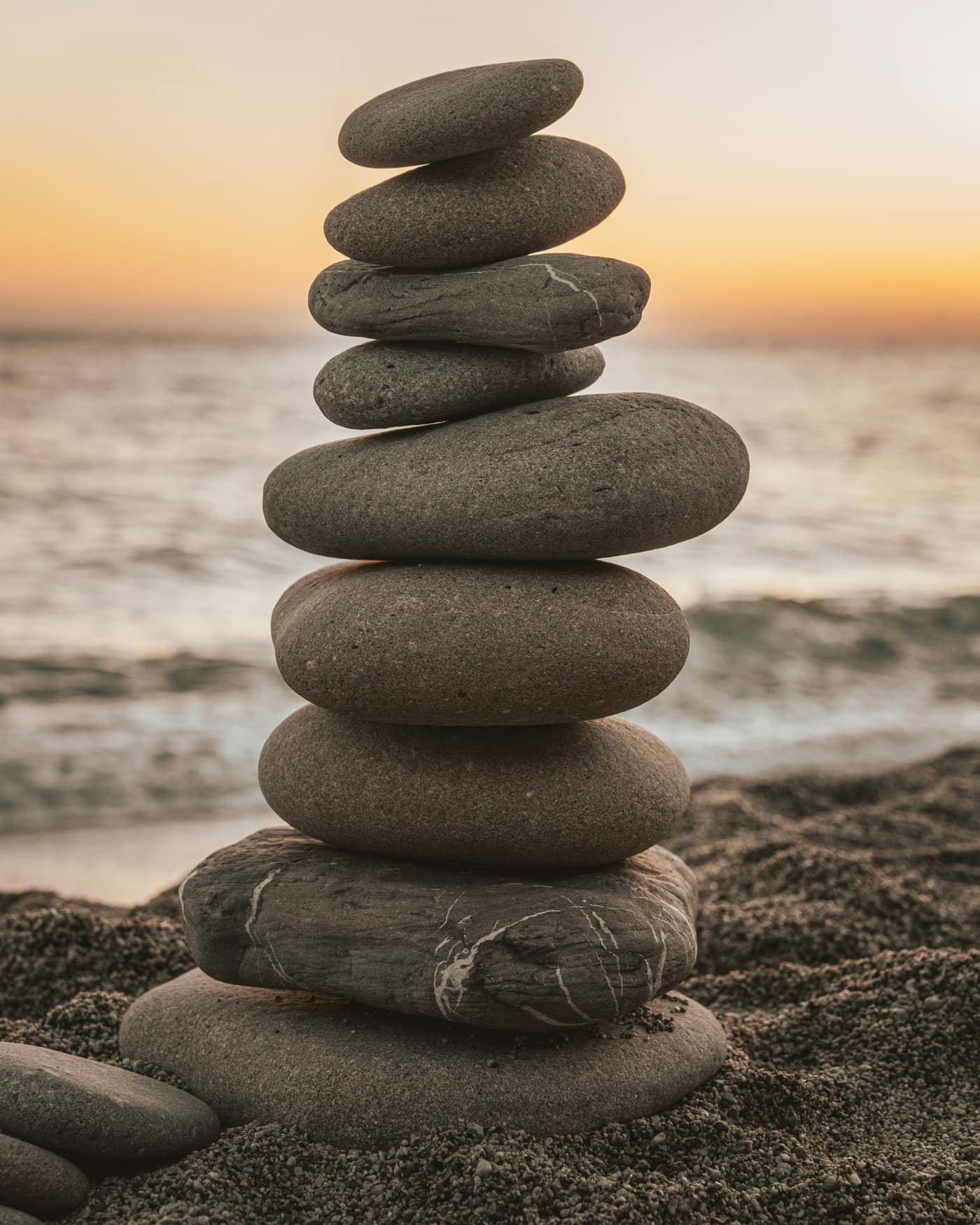 Piedras apiladas en equilibrio frente al mar al atardecer
